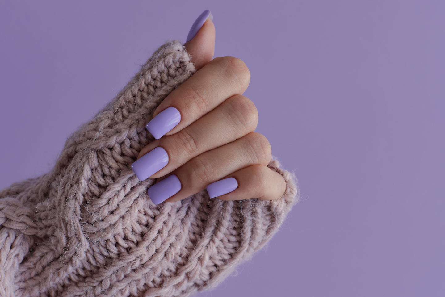 Female's hand with delicate nails of trendy lavender color